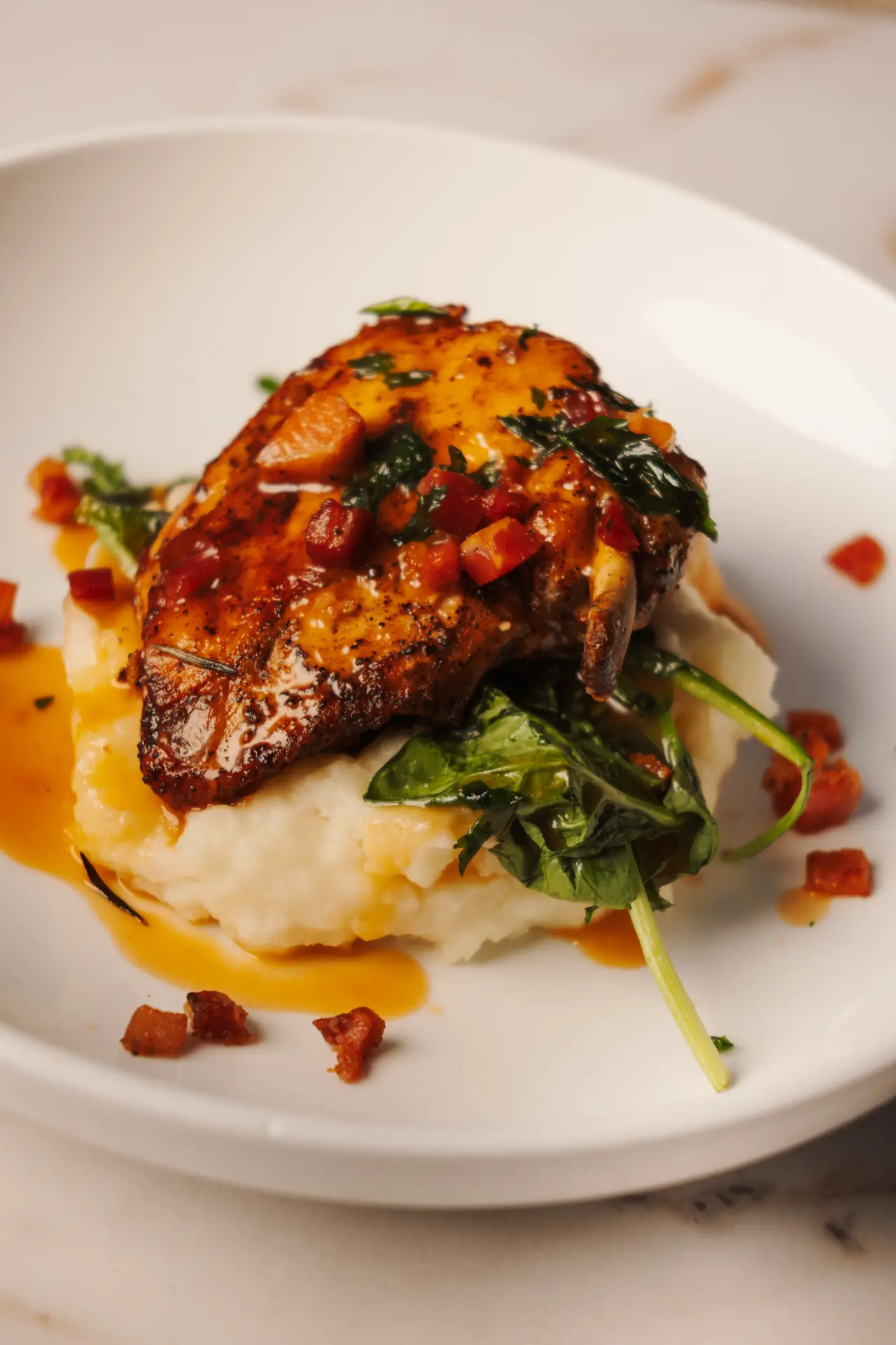 Seared pork chop over mashed potatoes with greens