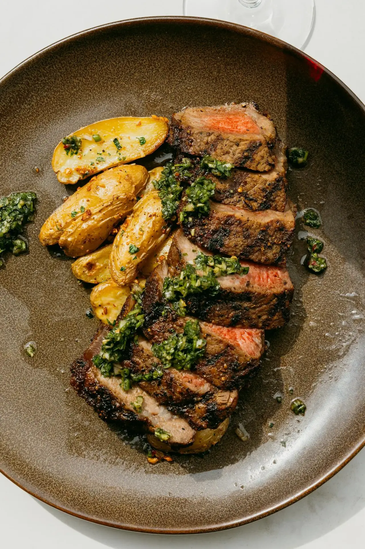 Sliced steak with potatoes and chimichurri