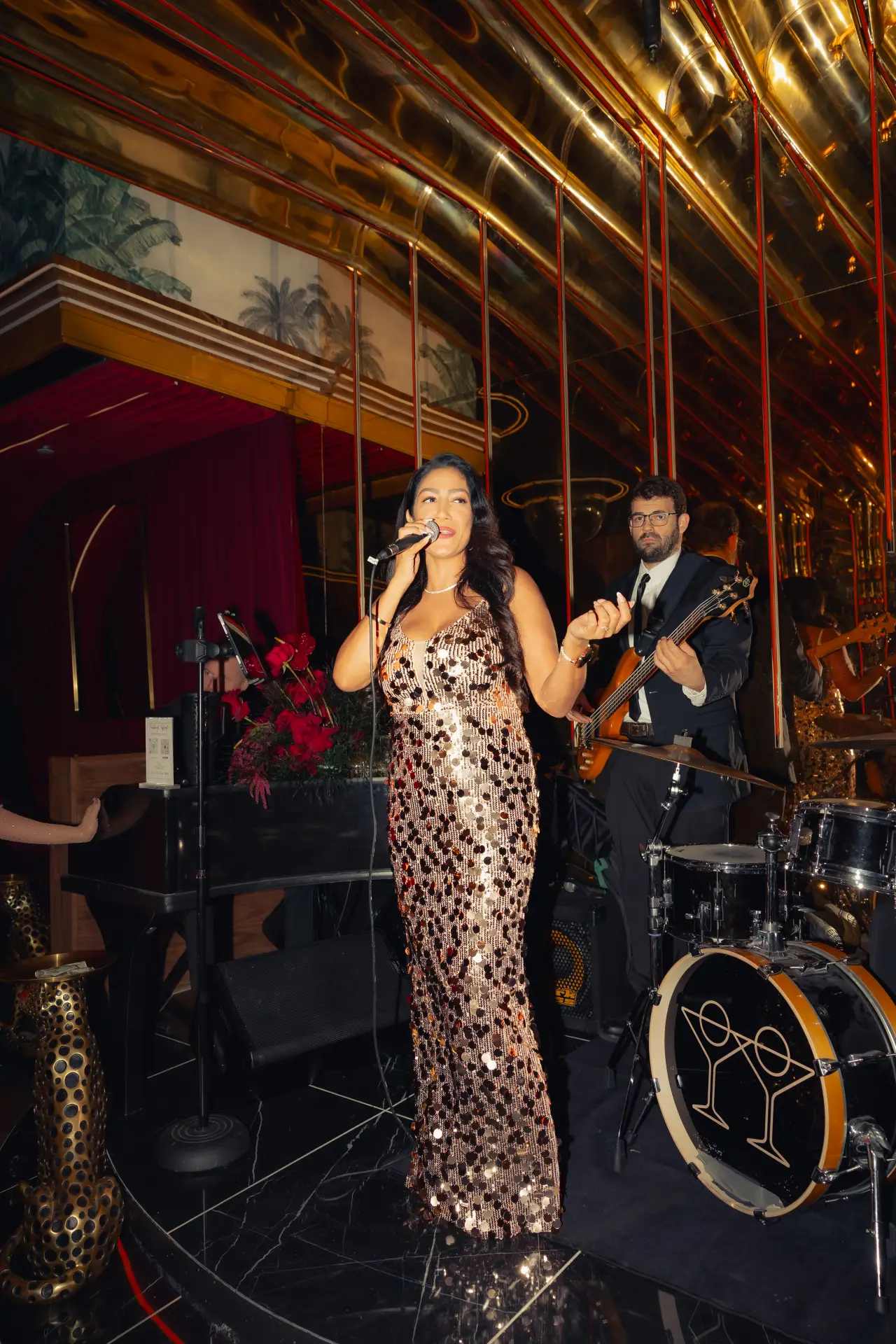 A singer and band performing on the stage at Tell Your Friends
