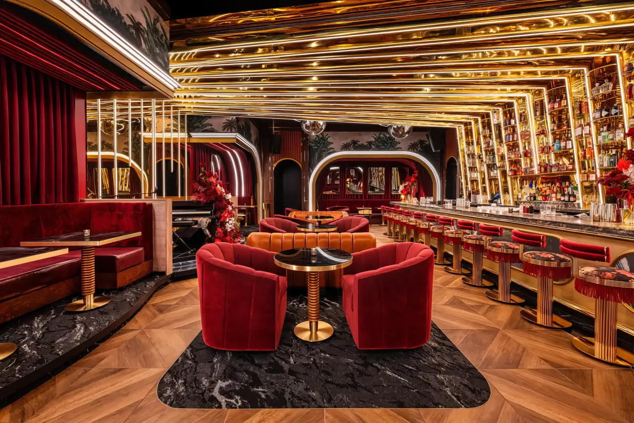 Red velvet chairs and the bar under gold arches