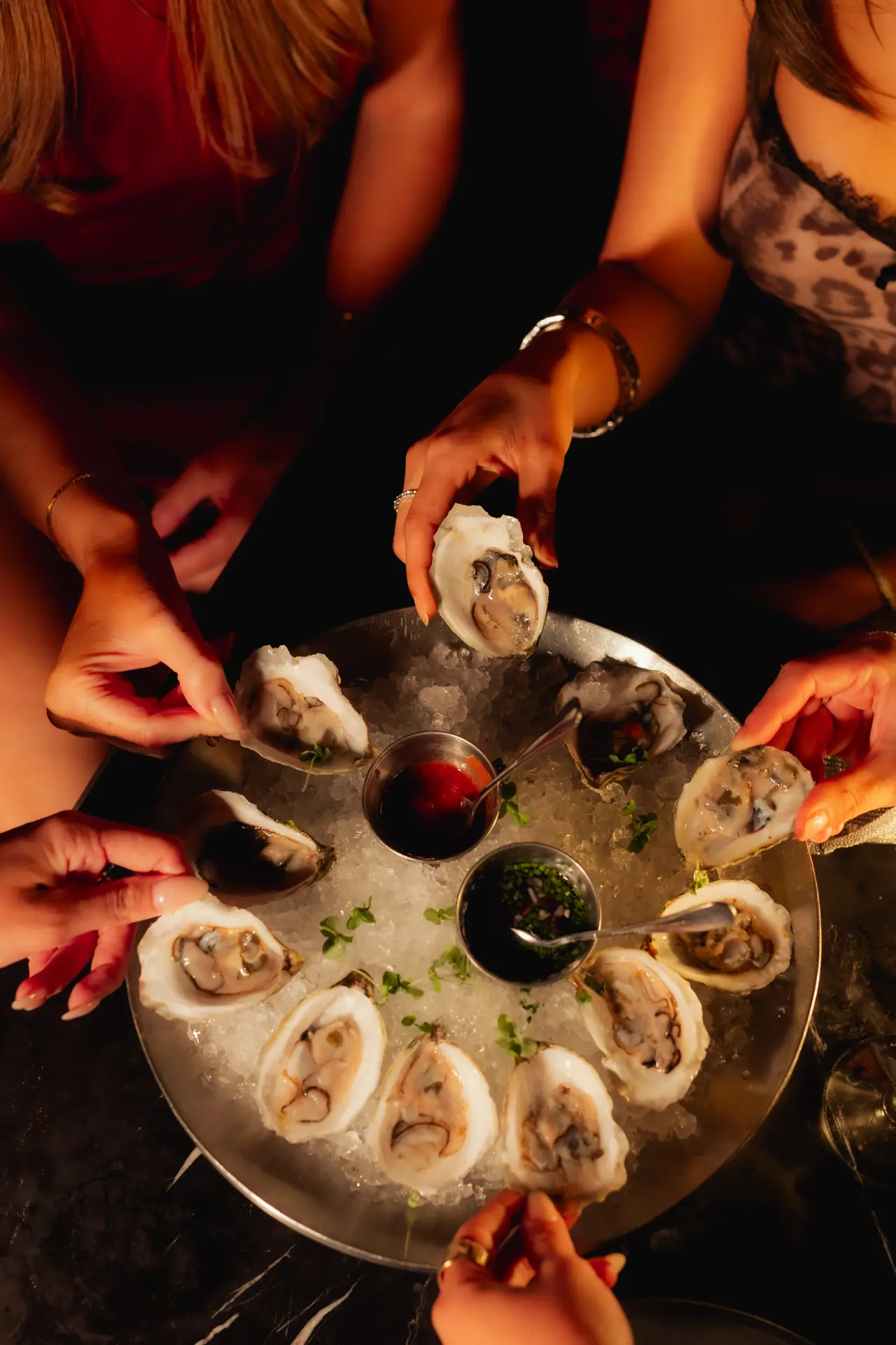 Friends reaching for oysters on ice